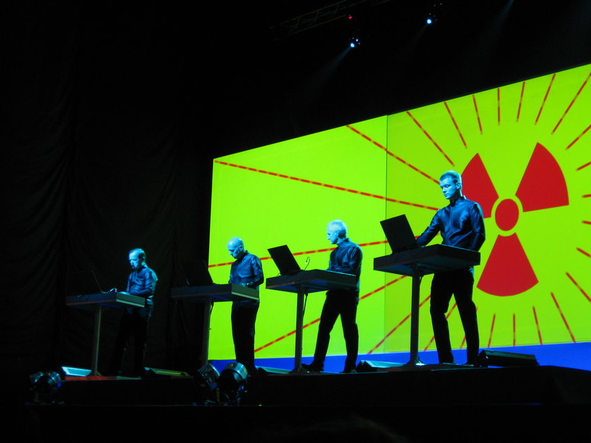 The German band Kraftwerk, one of the pioneers of electronic music, is performing at a concert in 2008. The band members are using novel music instruments, such as vocoder.