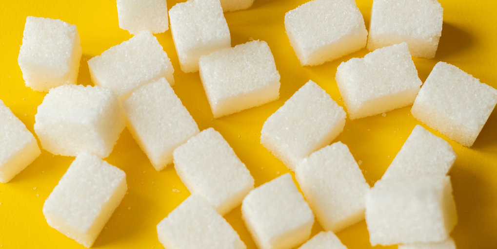 This photo shows numerous white sugar cubes set against a yellow background.