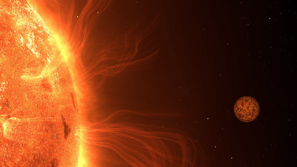 A close-up of a star dominates the left side of the image. Its surface glows intensely in various shades of orange, showing irregular structures like darker spots. Delicate, glowing plasma filaments arc outward from the Sun's surface. On the right side of the image, a small rocky planet is visible, its reddish-brown surface marked with dark, mottled patterns. The background is black, dotted with a few white star-like points.