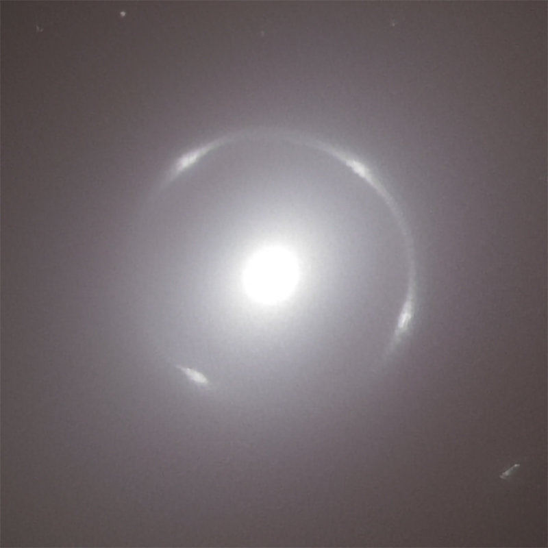 A bright, luminous point in the center with a circular, blurred halo, surrounded by dark space